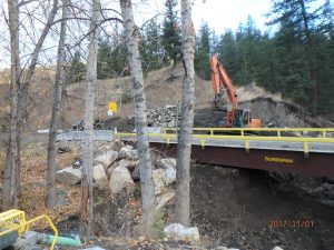 an angle of the surespan bridge rental with mountains and trees in the background. Rocks and dirt can be seen in the foreground.